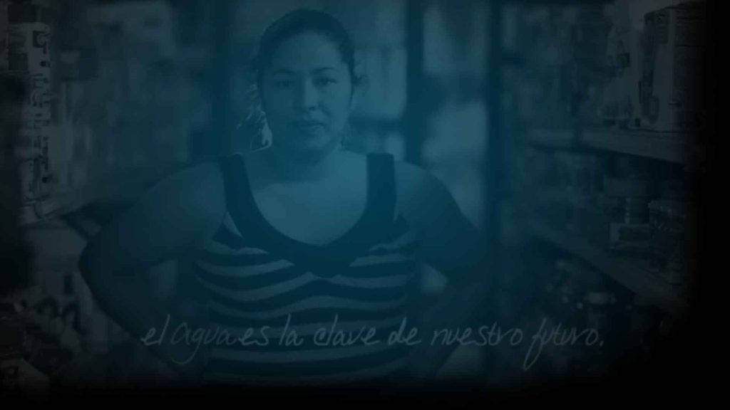 Still from Agua ad campaign featuring a woman standing in a grocery store with the words "el agua es la clave de nuestro futuro." Flavorlab Score provided original music to the ad campaign.|