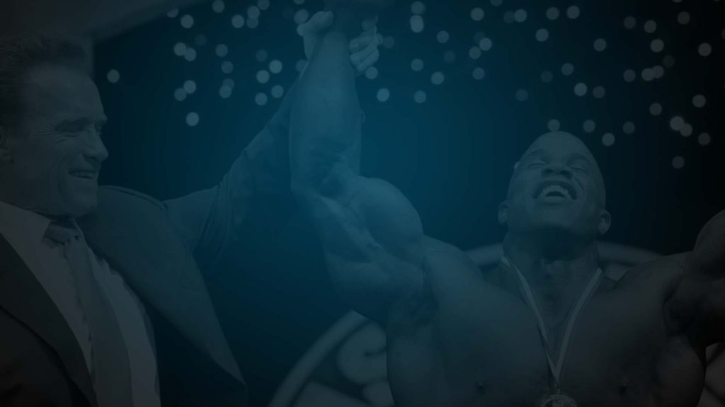 Still of a body builder having his arm lifted in victory by Arnold Schwarzenegger from film Generation Iron. Flavorlab Sound provided audio post production for the film.|