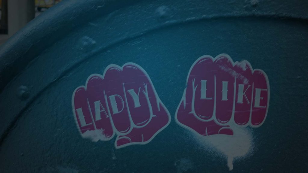 Still of two pink stickers in the shape of fists with the words "Lady Like" written across the knuckles. Flavorlab Sound provided mix for the series.