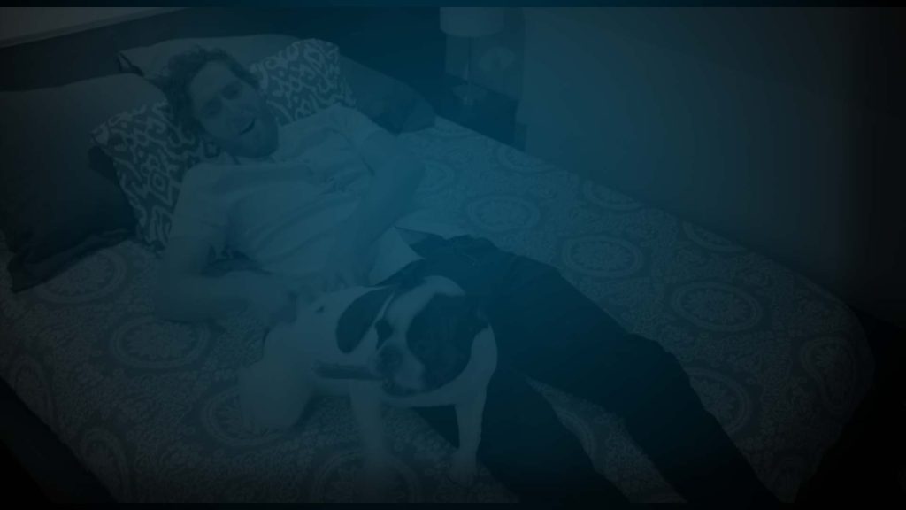 Still of Thomas Middleditch playing with a Boston Terrier on a bed. Producer's Toolbox provided music licensing for The Middle Of The Night Show.|Logo for the Middle of the Night Show|