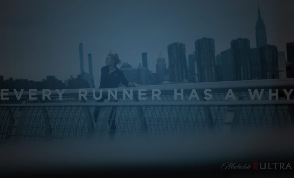 Still of a woman stretching her quads on a bridge in front of the city skyline in the #TeamULTRA Michelob Ultra ad. Producer's Toolbox provided music clearance and music licensing for the spot.|